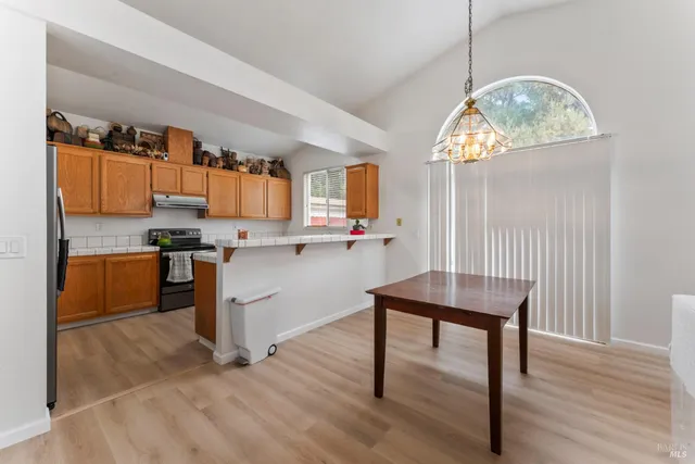 a dining room with wooden floor a chandelier a wooden table and chairs