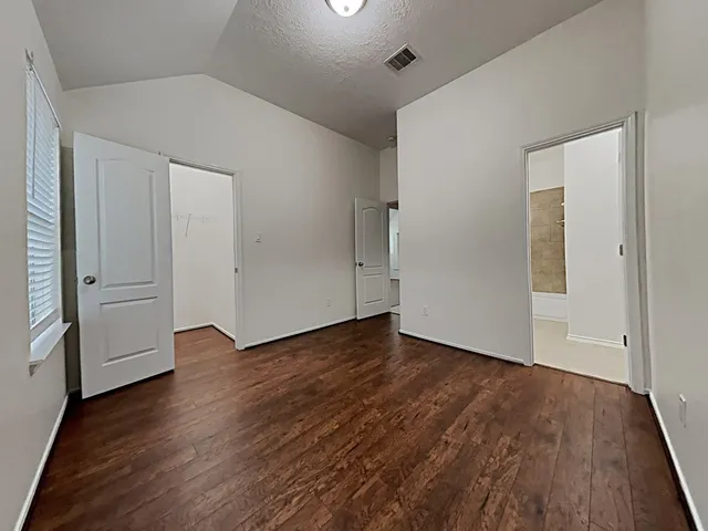 an empty room with wooden floor & windows