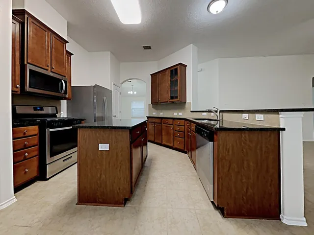 a kitchen with stainless steel appliances granite countertop a stove a sink and a refrigerator