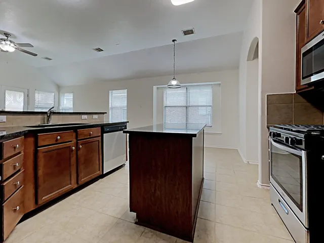 a kitchen with kitchen island granite countertop stainless steel appliances and wooden cabinets