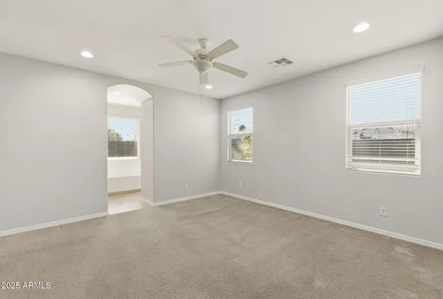 an empty room with ceiling fan and window