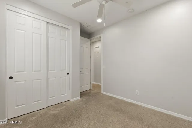 an empty room with a chandelier fan and windows