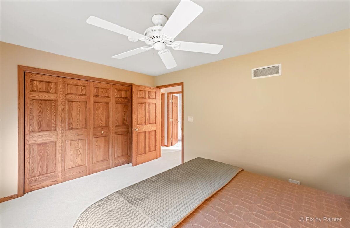 245 Perth Road Cary, IL 60013 - Photo 32 of 61 a bedroom with a bed and a chandelier fan