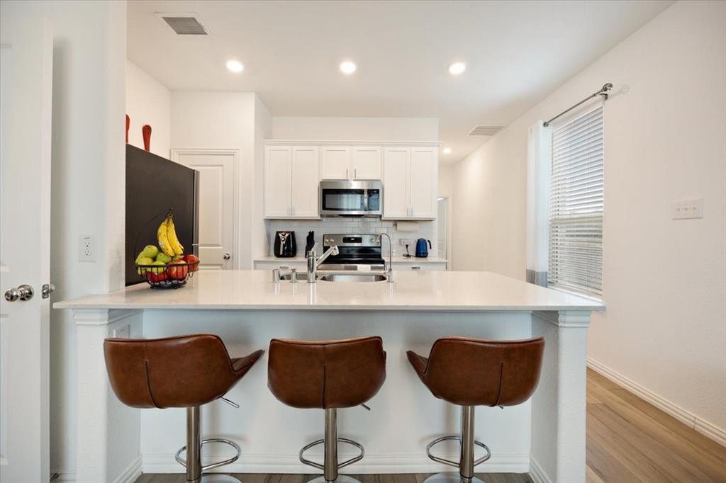 528 Poplar Street Princeton, TX 75407 - Photo 13 of 39 a kitchen with stainless steel appliances granite countertop a stove a sink and a refrigerator with wooden floor