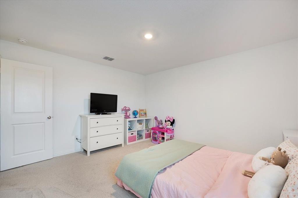 528 Poplar Street Princeton, TX 75407 - Photo 32 of 39 a bedroom with a bed and flat screen tv