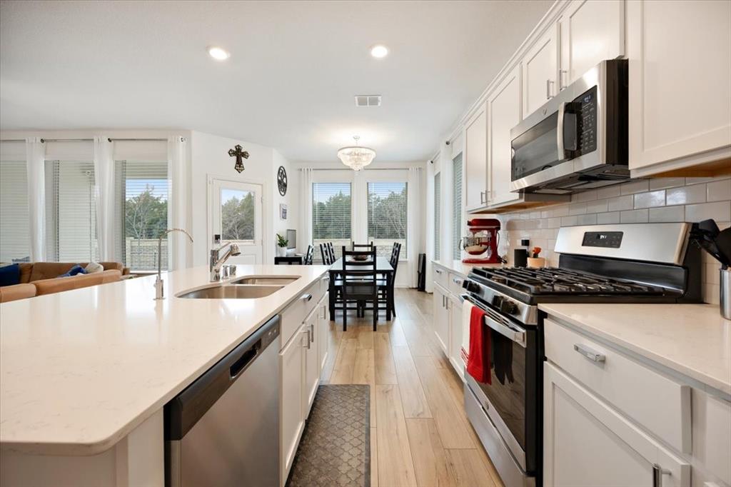 528 Poplar Street Princeton, TX 75407 - Photo 6 of 39 a kitchen with stainless steel appliances granite countertop a stove top oven a sink a dining table and chairs with white countertops