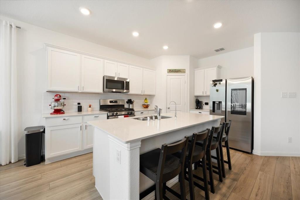 528 Poplar Street Princeton, TX 75407 - Photo 10 of 39 a kitchen with a sink a stove a refrigerator and white cabinets with wooden floor