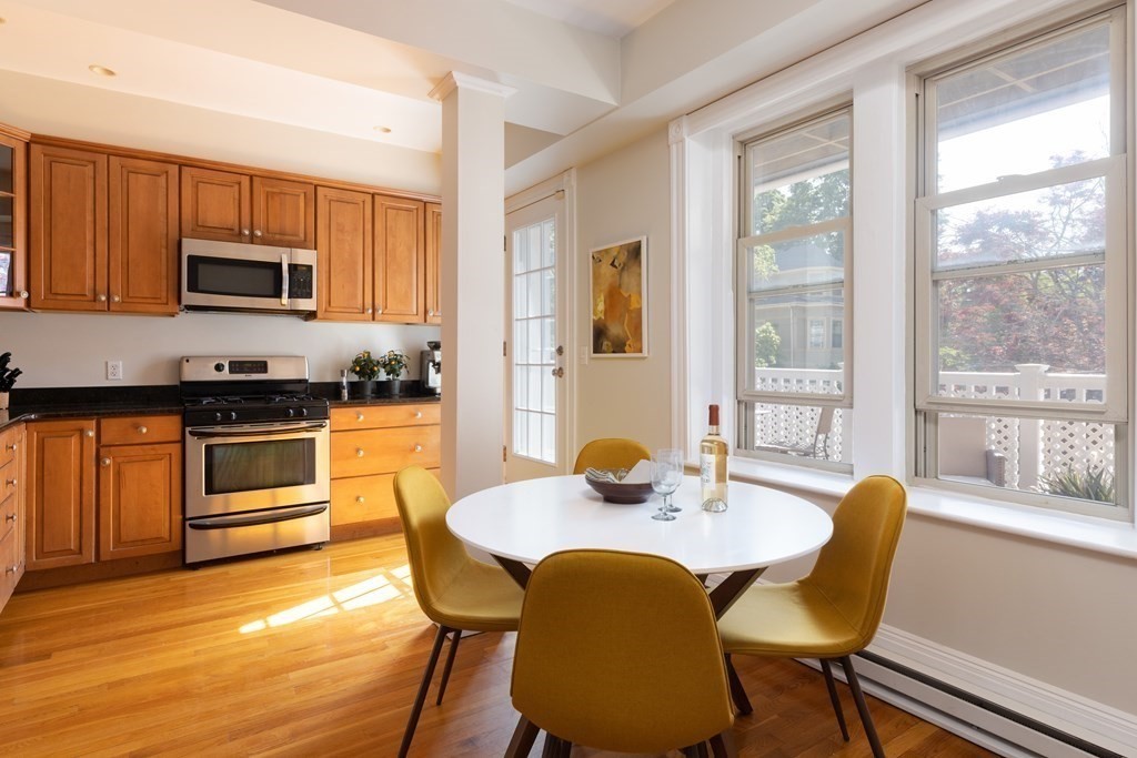 152 Harvard Street, Unit 4 Brookline, MA 02446 - Photo 7 of 26 a kitchen with stainless steel appliances kitchen island granite countertop a stove a sink a table and chairs