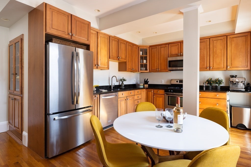 152 Harvard Street, Unit 4 Brookline, MA 02446 - Photo 8 of 26 a kitchen with stainless steel appliances wooden floor dining table and chairs