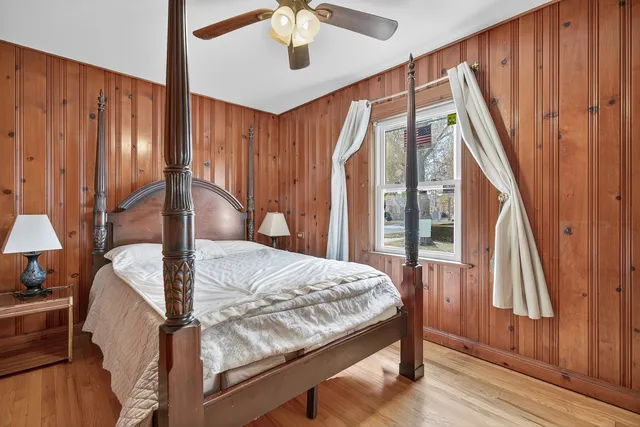 a bedroom with a bed and a large mirror with wooden floor