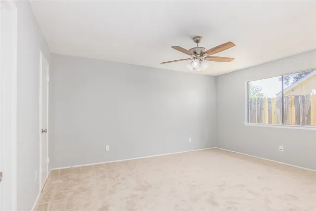 an empty room with windows and ceiling fan