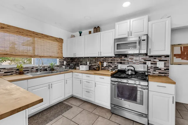 a kitchen with stainless steel appliances granite countertop white cabinets sink stove and microwave