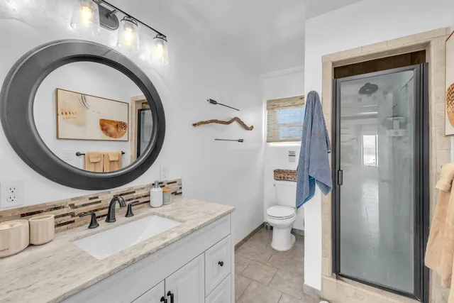 a bathroom with a granite countertop toilet a sink and a mirror