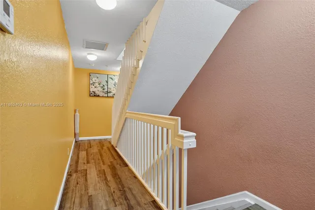 a view of a hallway with wooden floor and staircase
