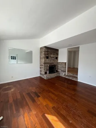 a view of empty room with wooden floor and fireplace