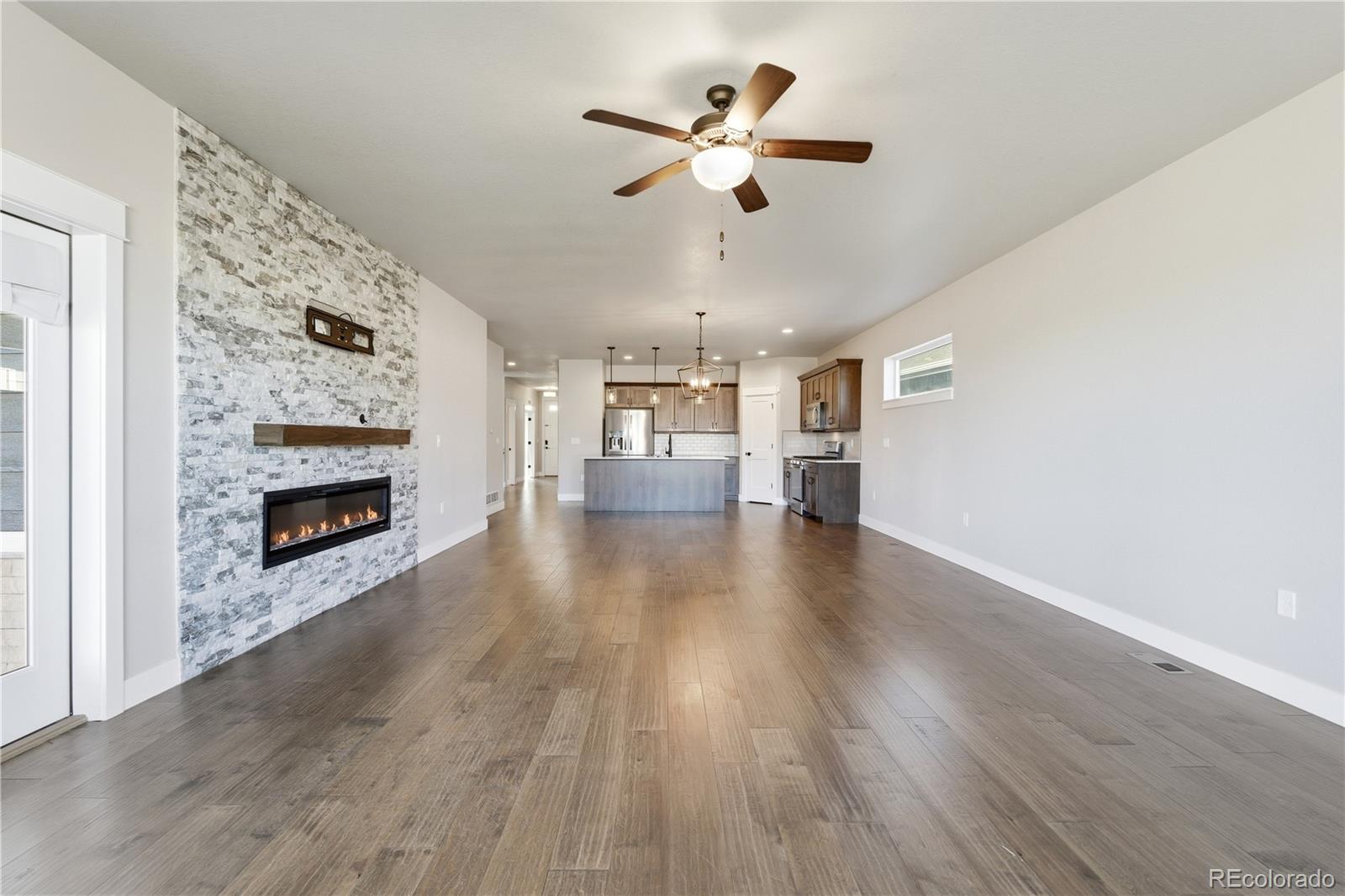1908 Tidewater Lane Windsor, CO 80550 - Photo 2 of 41 a view of a room with wooden floor a ceiling fan a fireplace and entryway
