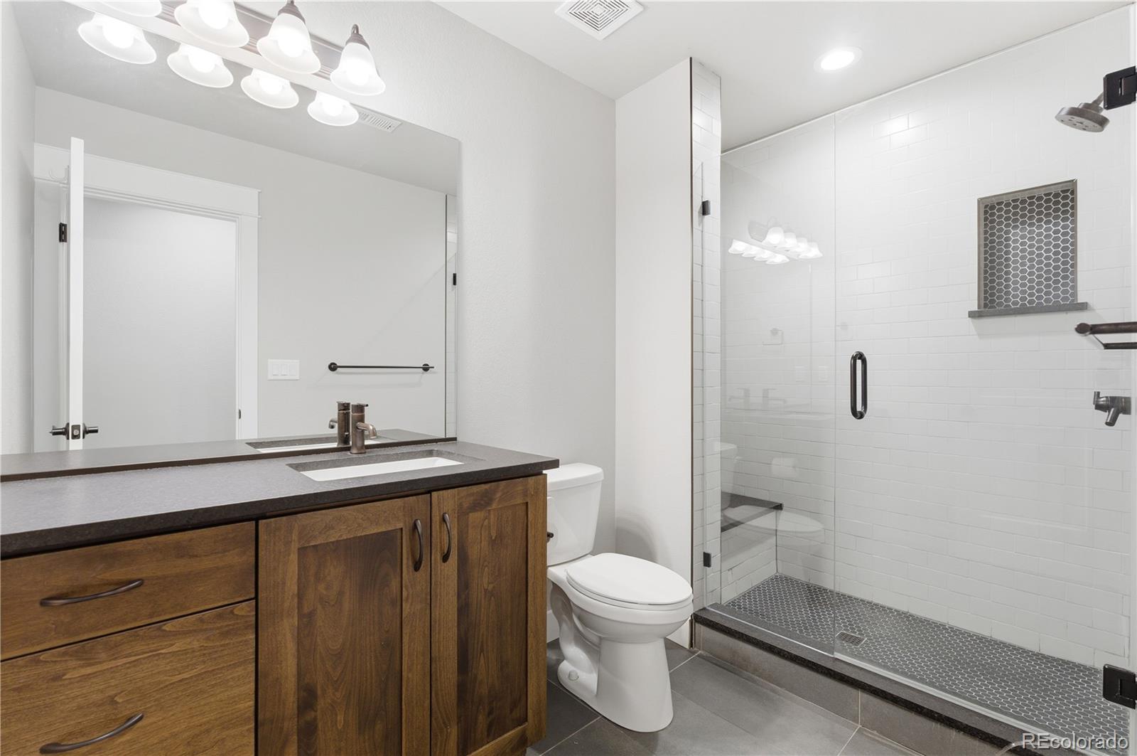 1908 Tidewater Lane Windsor, CO 80550 - Photo 29 of 41 a bathroom with a granite countertop sink a toilet and a mirror