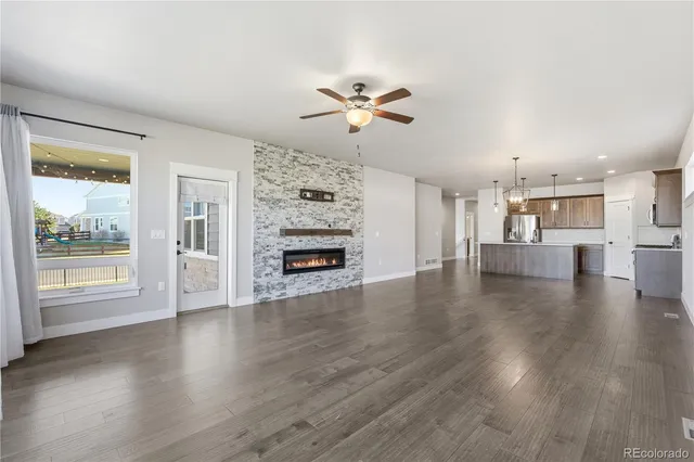 a view of a livingroom with wooden floor a ceiling fan and windows
