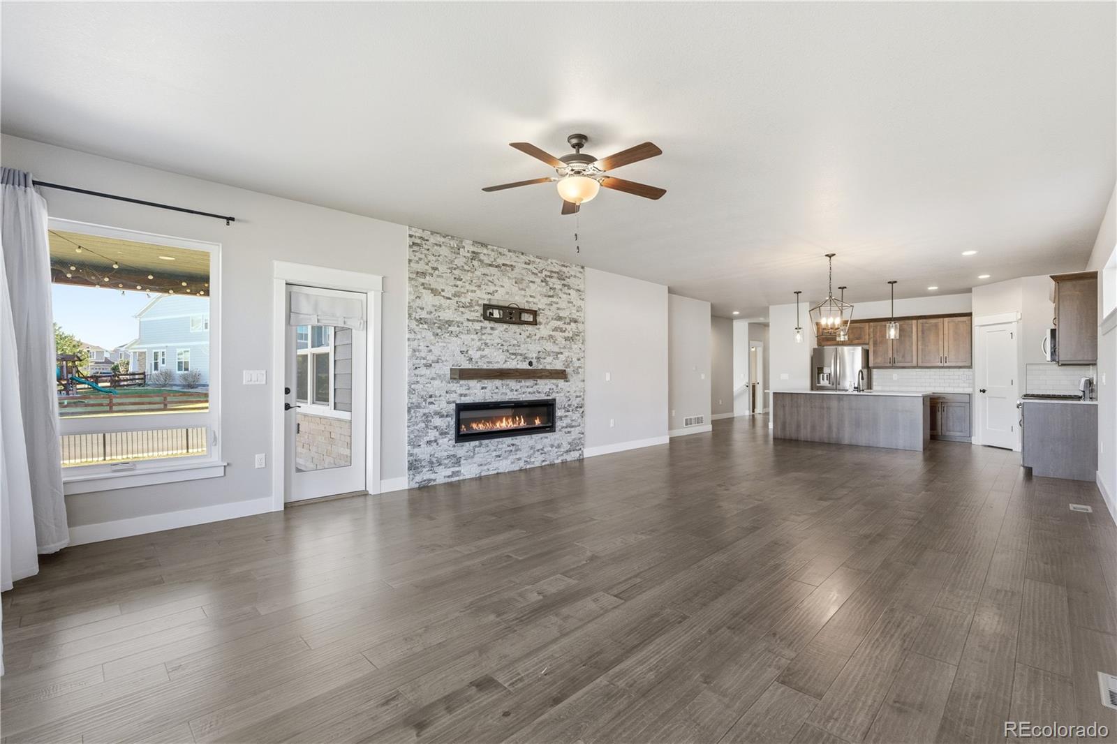 1908 Tidewater Lane Windsor, CO 80550 - Photo 4 of 41 a view of a livingroom with wooden floor a ceiling fan and windows
