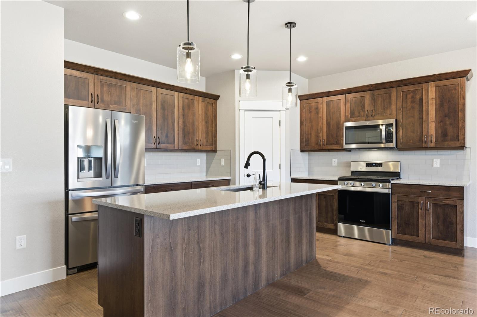 1908 Tidewater Lane Windsor, CO 80550 - Photo 5 of 41 a kitchen with stainless steel appliances granite countertop a sink refrigerator and microwave