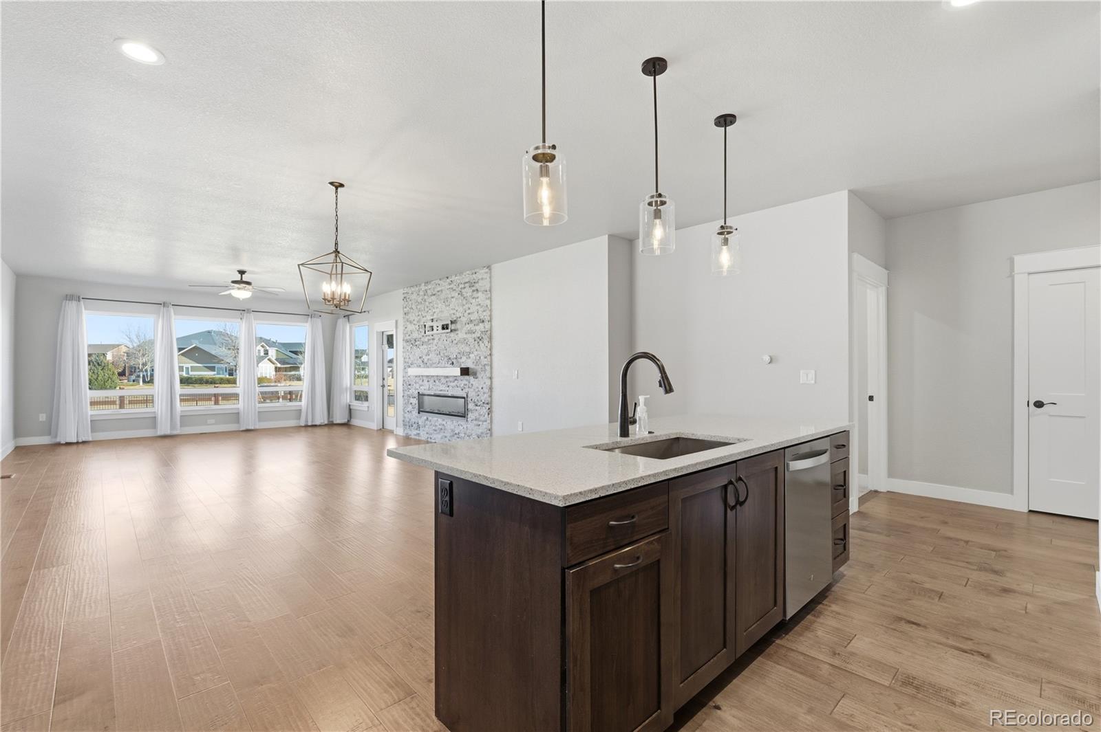 1908 Tidewater Lane Windsor, CO 80550 - Photo 6 of 41 a kitchen with a sink a center island a stove and a wooden floor