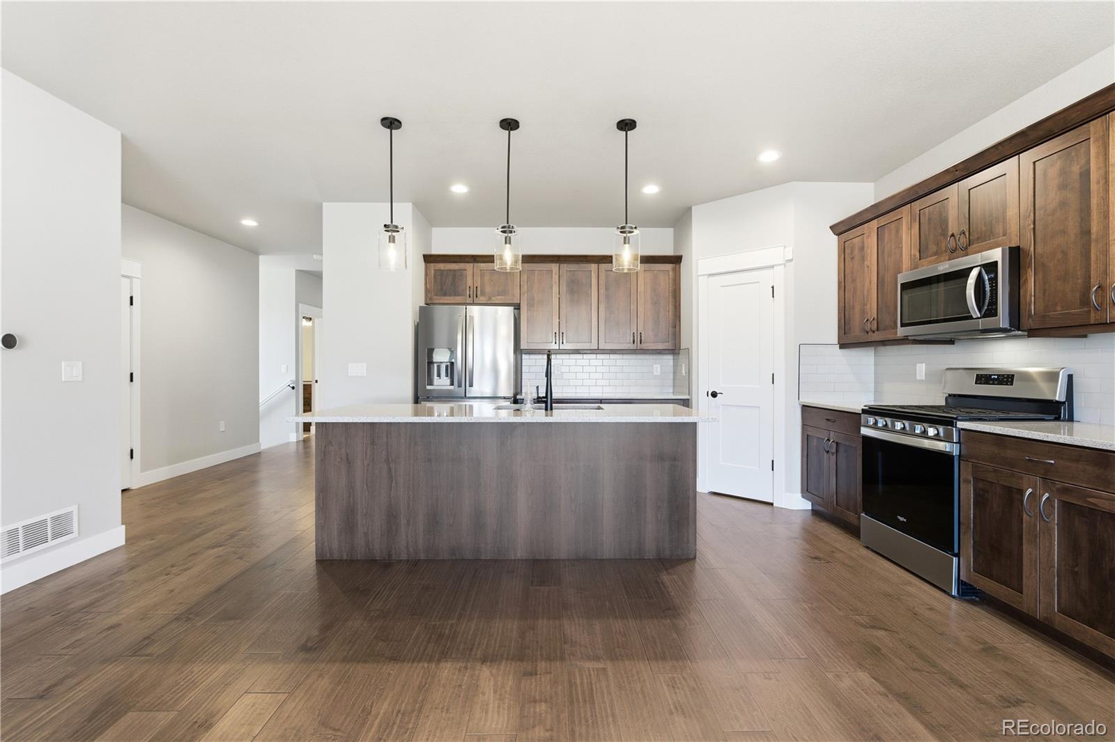 1908 Tidewater Lane Windsor, CO 80550 - Photo 7 of 41 a kitchen with stainless steel appliances granite countertop a refrigerator a oven a sink and white cabinets with wooden floor