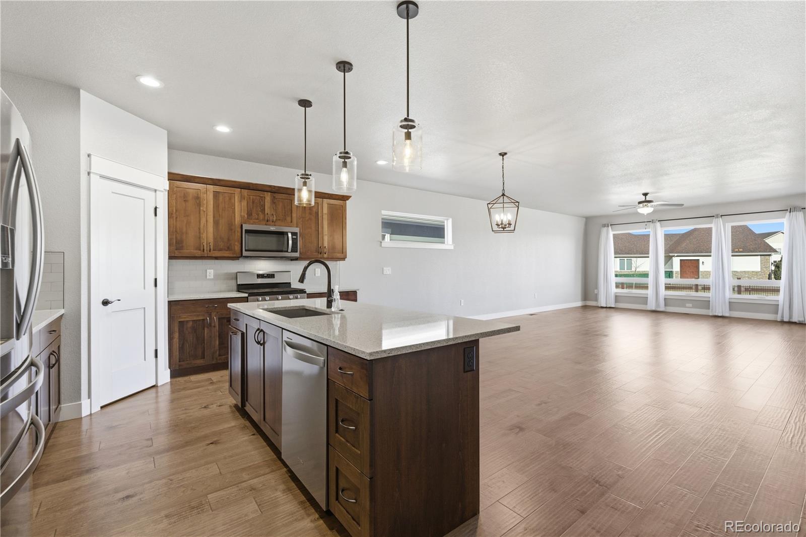 1908 Tidewater Lane Windsor, CO 80550 - Photo 8 of 41 a kitchen with a sink a center island a stove and a wooden floor