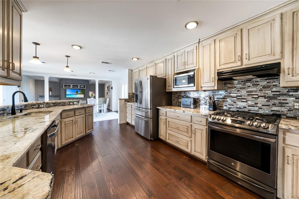 750 Long Road Lucas, TX 75002 - Photo 17 of 39 a kitchen with stainless steel appliances granite countertop a stove top oven a sink dishwasher and a refrigerator with wooden floor