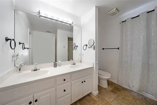a bathroom with a double vanity sink a toilet and a mirror