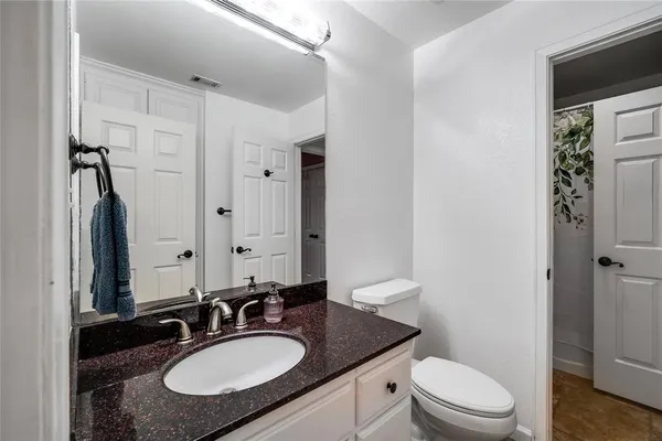 a bathroom with a granite countertop sink toilet a mirror and shower