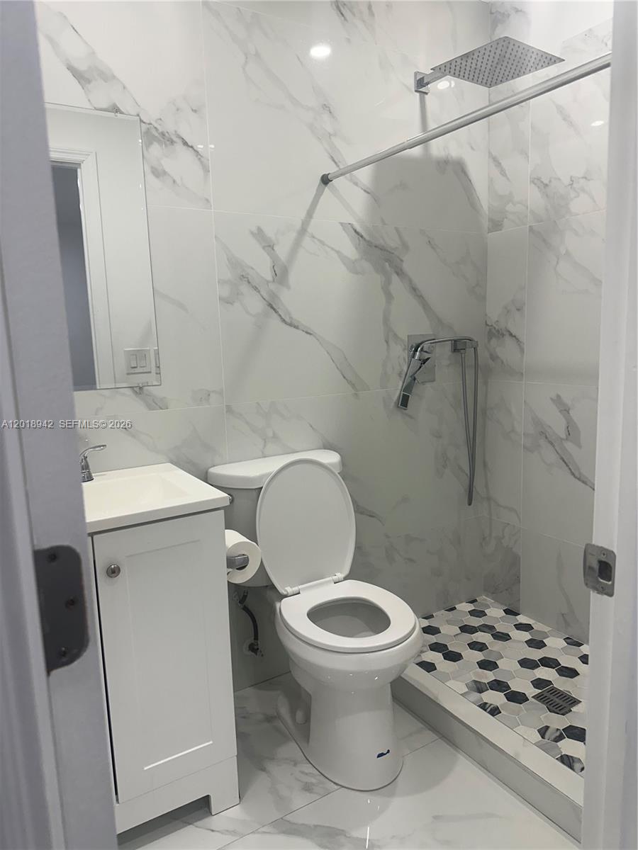 13740 Southwest 282nd Street, Unit 1 Homestead, FL 33033 - Photo 6 of 9 a white toilet sitting next to a bathroom sink and a shower