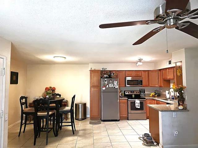 a kitchen with stainless steel appliances kitchen island granite countertop a table chairs and a refrigerator
