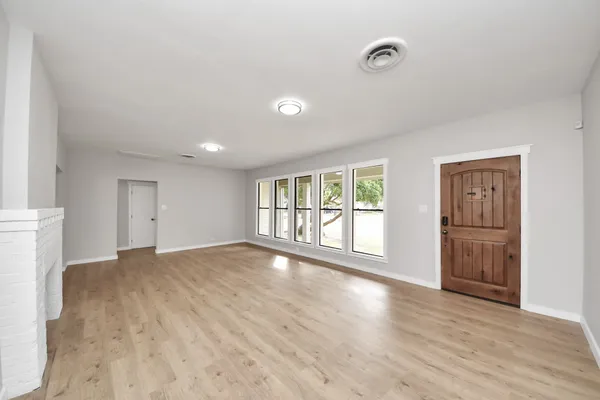 a view of an empty room with a window and wooden floor