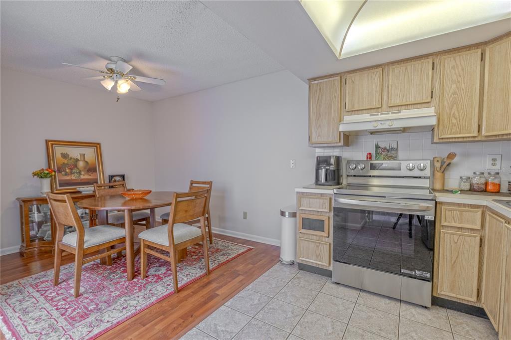 1131 Orange Tree Circle West, Unit C Palm Harbor, FL 34684 - Photo 10 of 28 a kitchen with a table chairs and a refrigerator