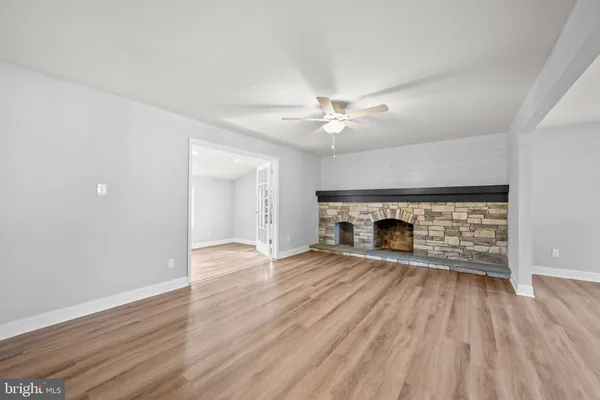 an empty room with wooden floor fireplace and windows
