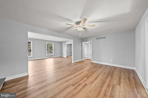 a view of an empty room with window and wooden floor