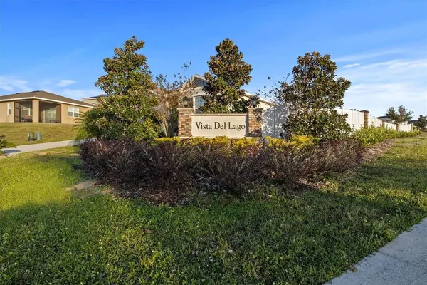 a sign that is sitting in front of a house with a big yard