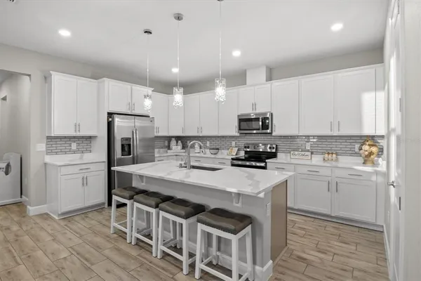 a kitchen with a sink a stove a refrigerator and white cabinets