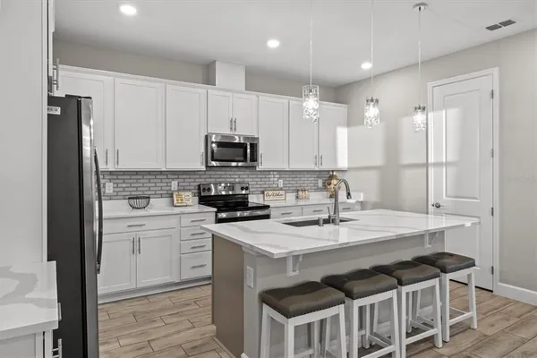 a kitchen with a sink a stove a refrigerator and white cabinets