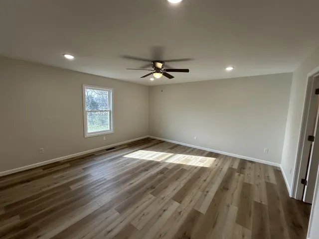 an empty room with wooden floor and windows