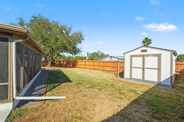 a view of backyard with large tree and wooden fence