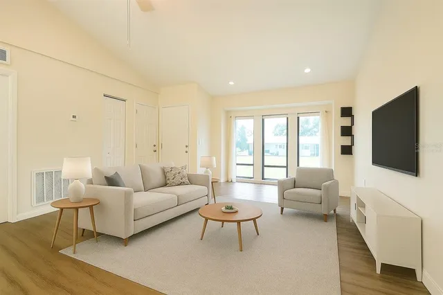 a living room with furniture a flat screen tv and a large window