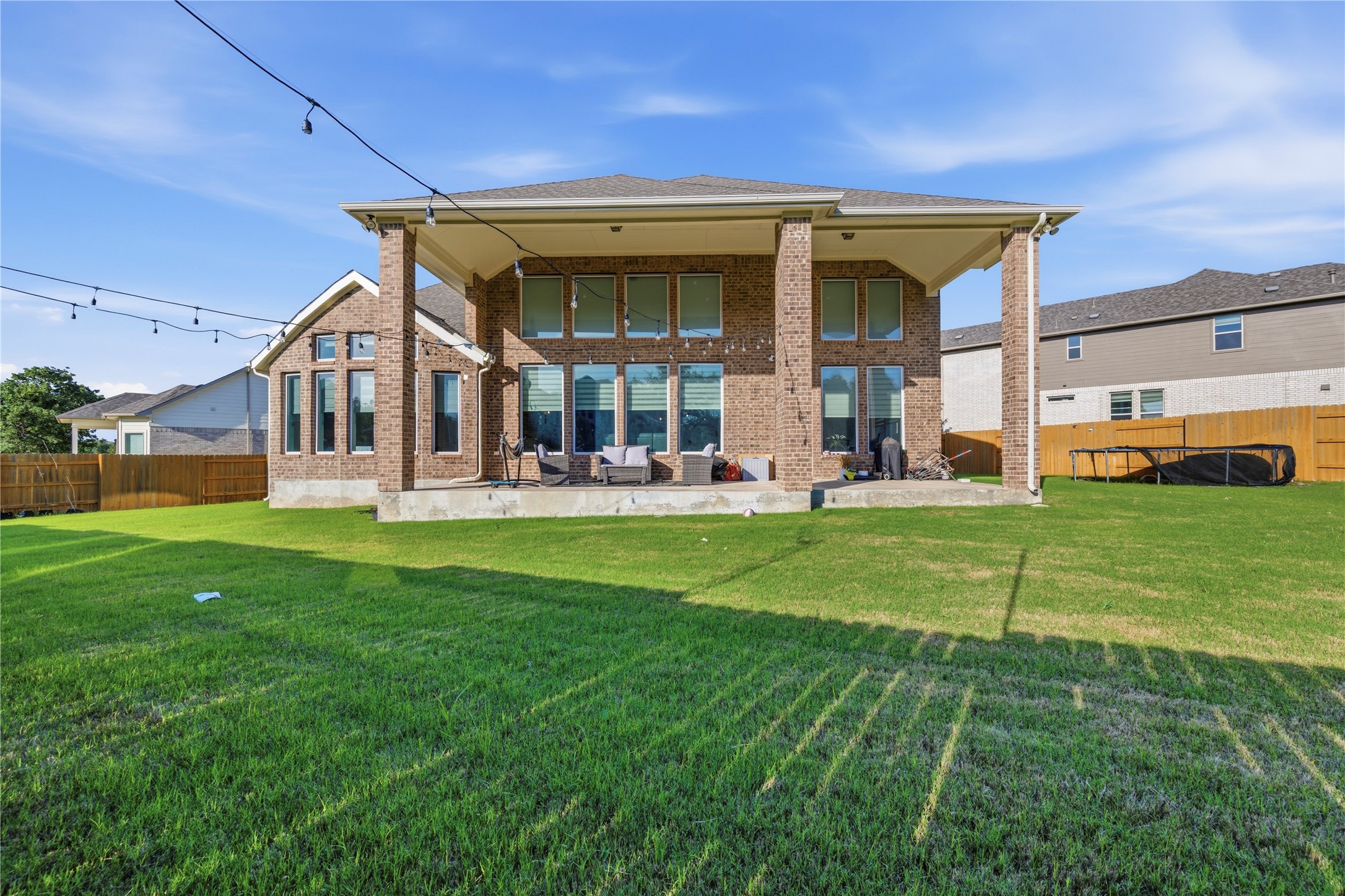 105 Autumn Oak Way Georgetown, TX 78628 - Photo 38 of 40 Expansive rear yard featuring a covered patio, brick exterior, multiple windows, and a wood privacy fence