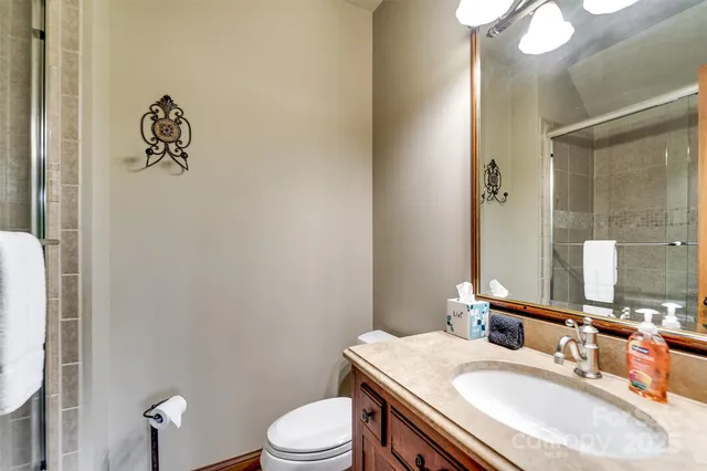 a bathroom with a granite countertop sink vanity mirror and toilet