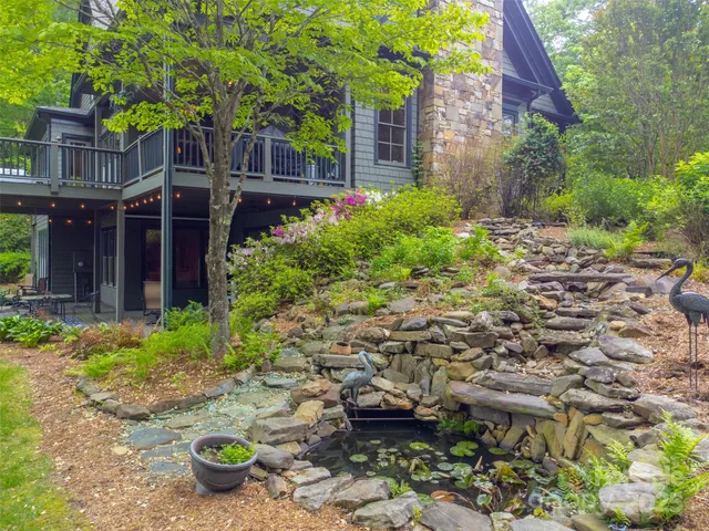 a backyard of a house with table and chairs plants and large tree
