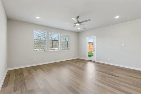 an empty room with wooden floor cabinet and windows