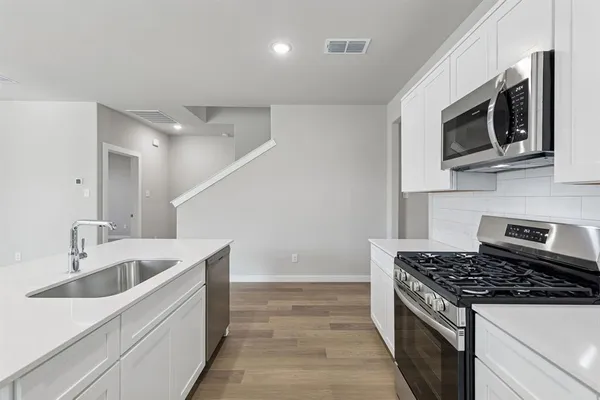 a view of kitchen with granite countertop cabinets and refrigerator