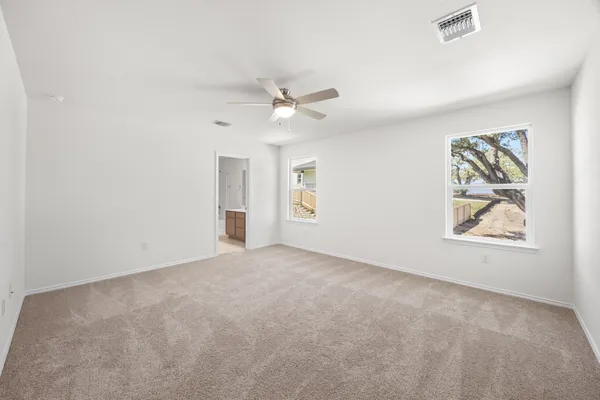 an empty room with windows and ceiling fan