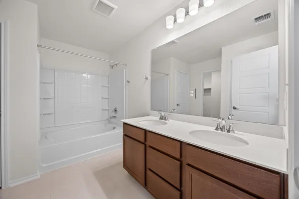 a bathroom with a sink double vanity granite tub shower and a mirror