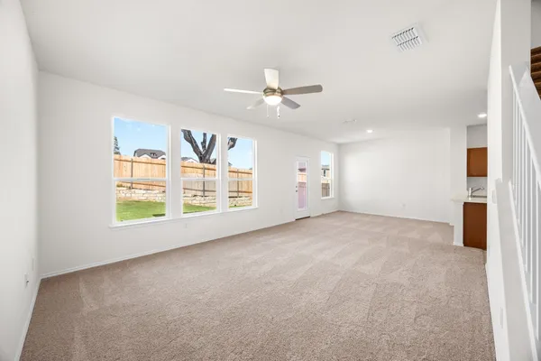 an empty room with chandelier fan and windows